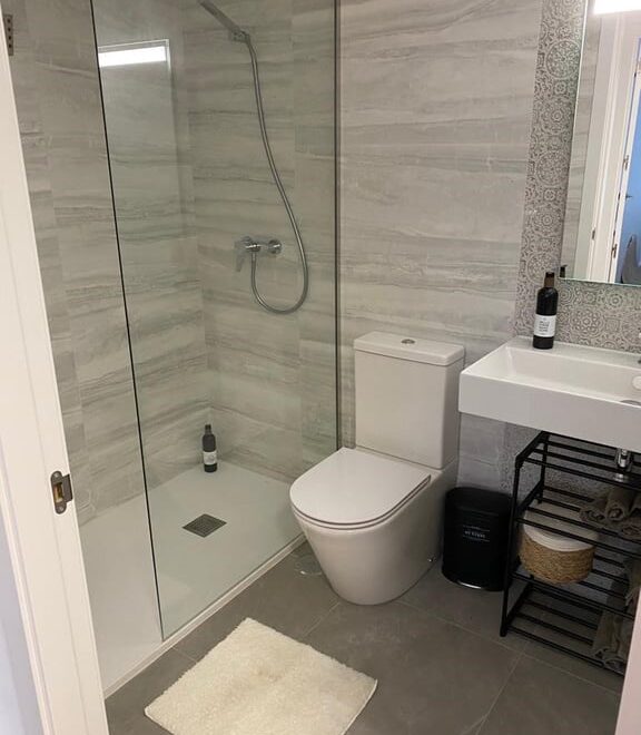 Baño moderno con ducha y lavabo.